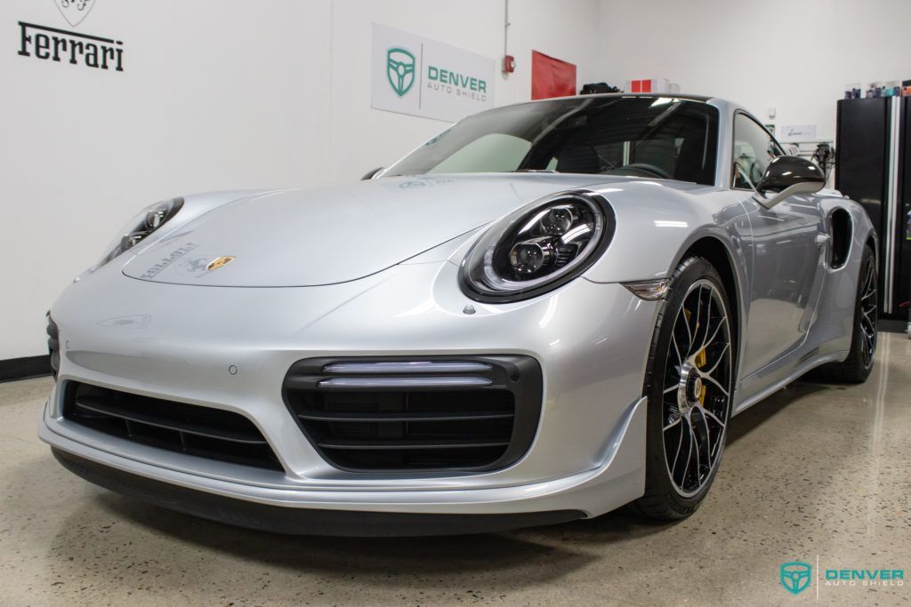 A silver porsche 911 turbo s is parked in a garage.