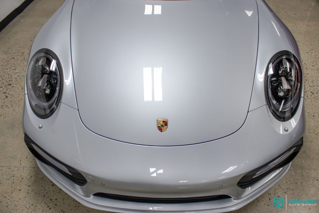 A silver porsche 911 is parked in a garage.