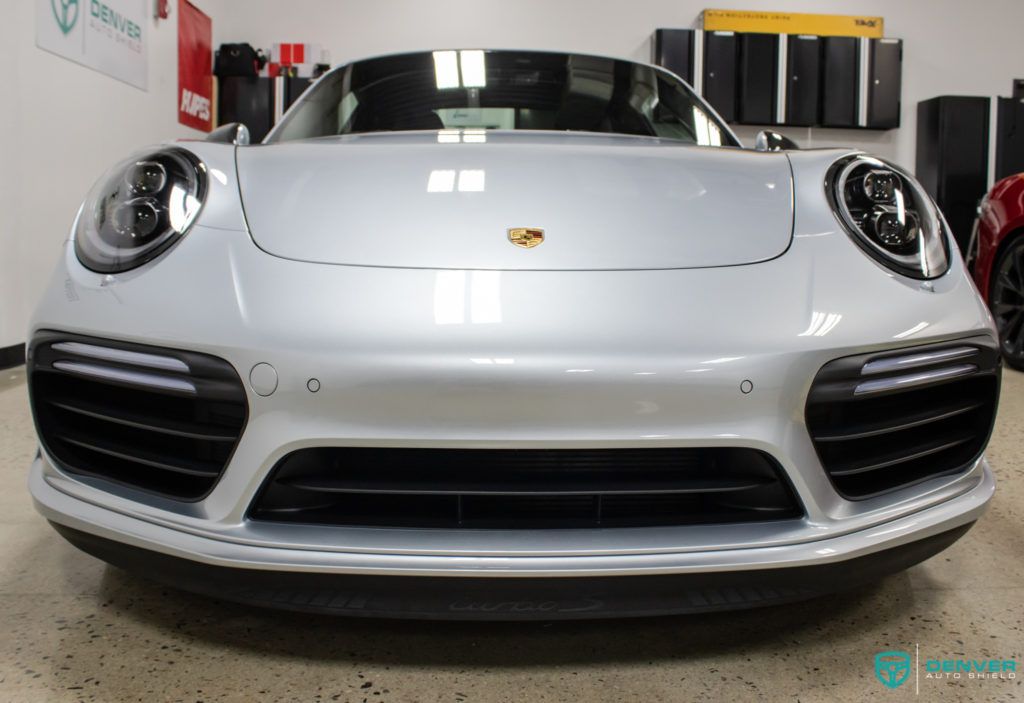 A silver porsche is parked in a garage