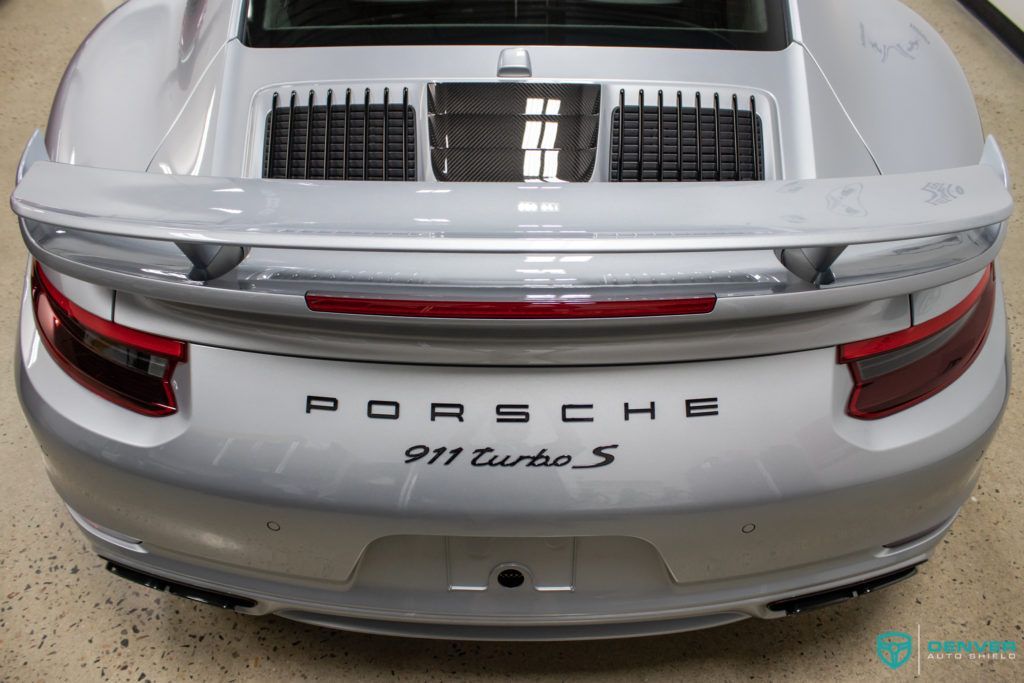 A silver porsche 911 turbo s is parked in a garage.