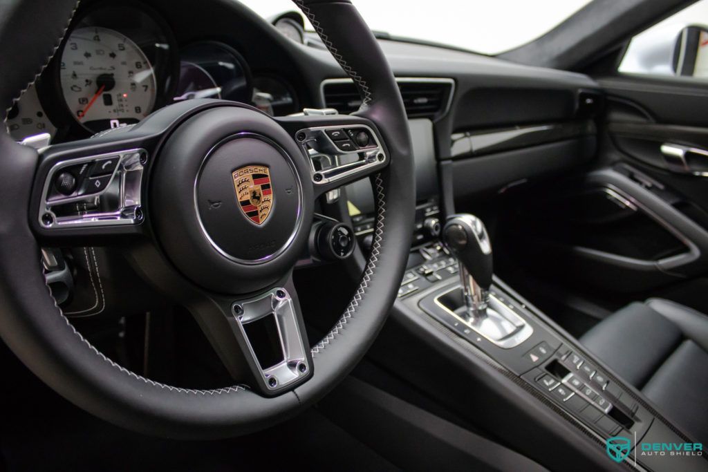 A close up of a porsche 911 steering wheel and dashboard.