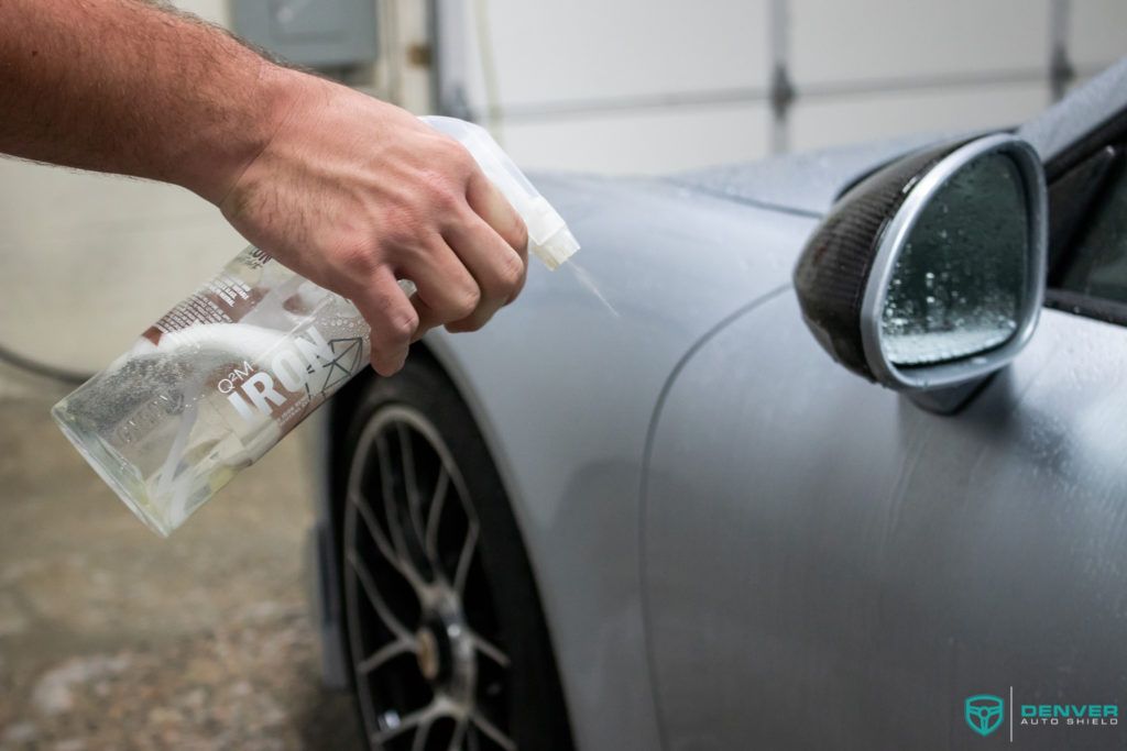 A person is spraying a car with a spray bottle.