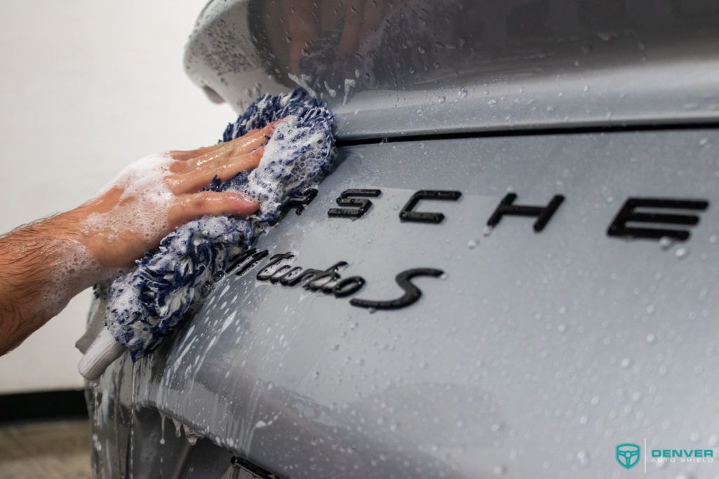 A person is washing a porsche turbo s with a towel.