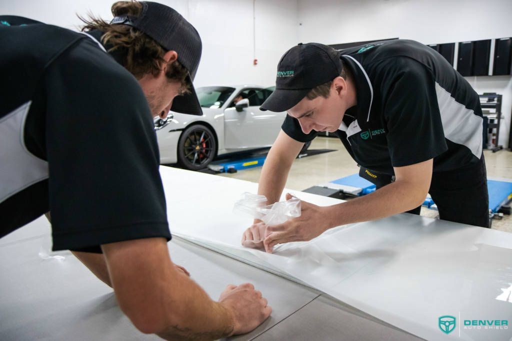 Two men are working on a car in a garage.