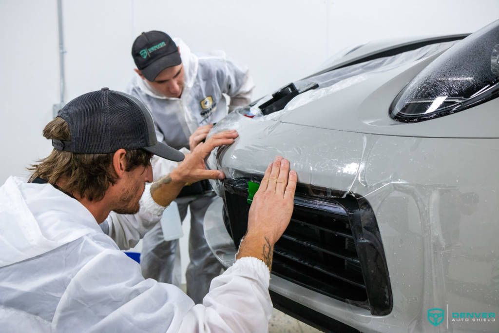 Two men are working on a car in a garage.