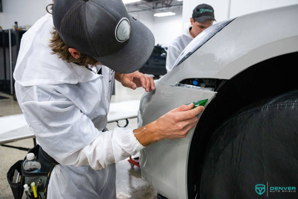 A man in a hat is working on a car in a garage.