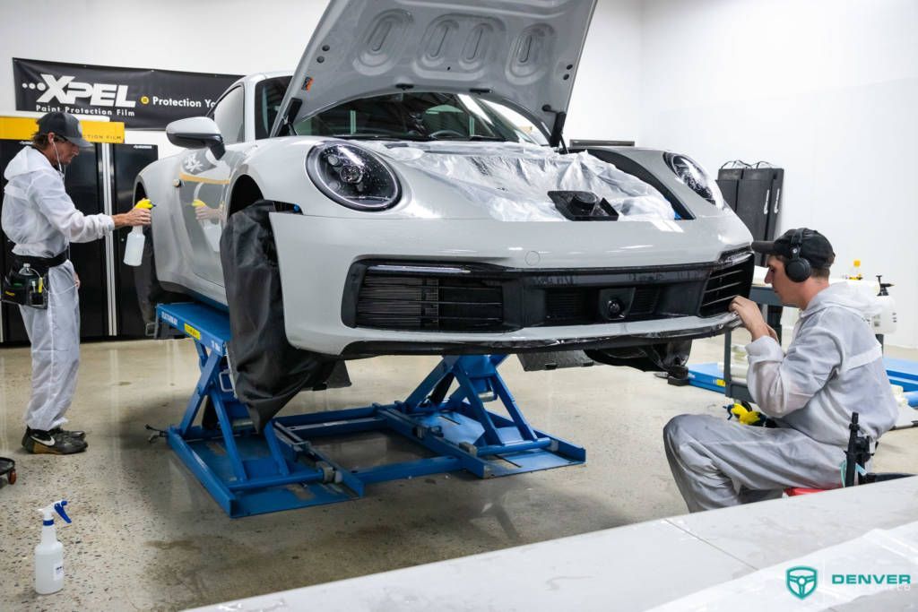 Two men are working on a white car in a garage.