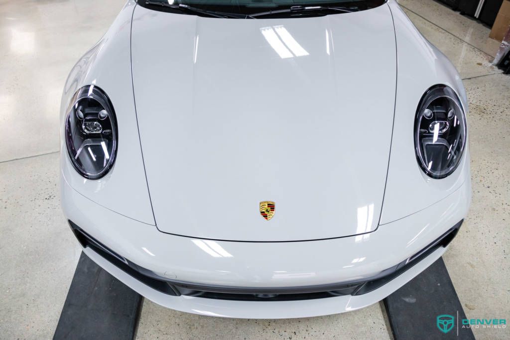 A white porsche 911 is sitting on a black mat in a garage.