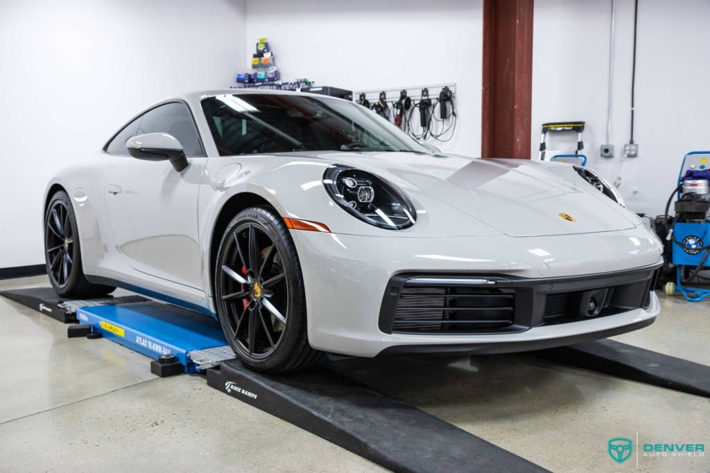 A white porsche 911 is parked on a lift in a garage.