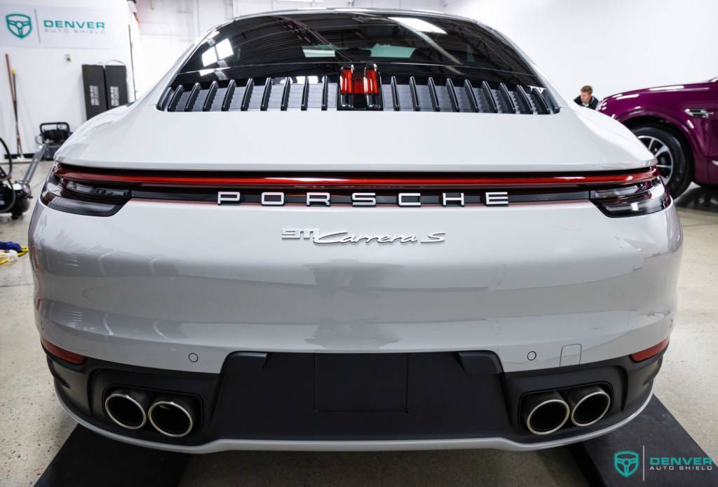 A white porsche 911 carrera is parked in a garage.