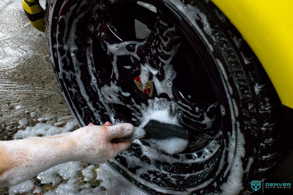 A person is cleaning a tire with a brush and soap.