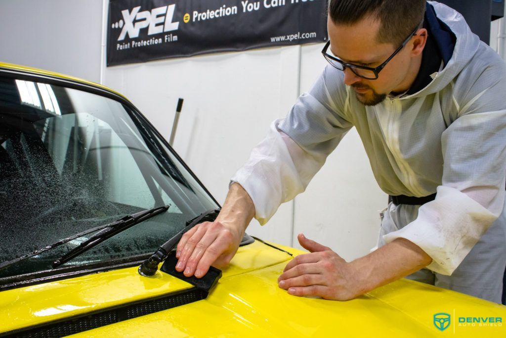 A man is polishing a yellow car with a cloth.