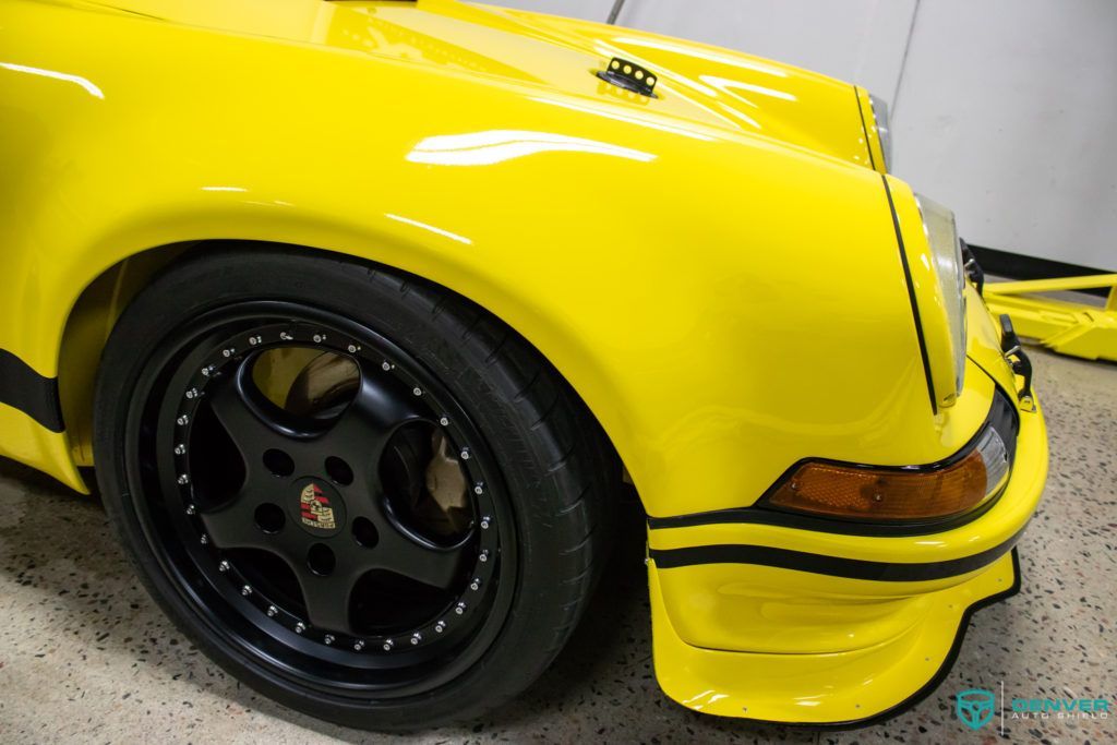 A yellow porsche 911 is parked in a garage.