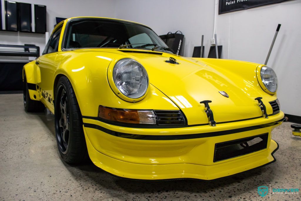 A yellow porsche is parked in a garage.