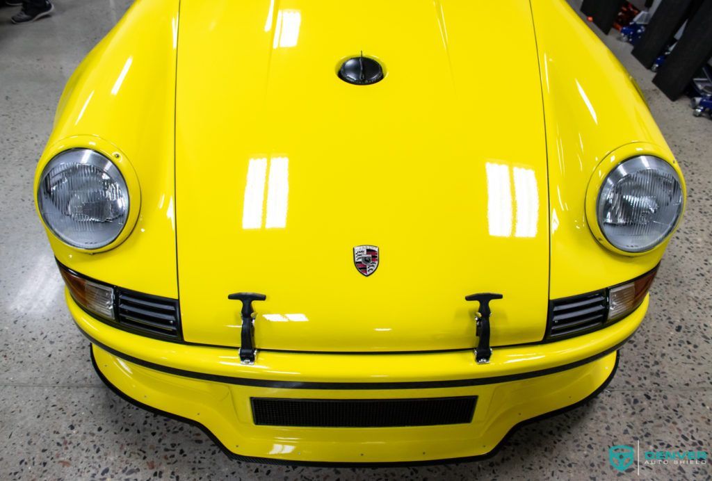 A yellow porsche is parked in a garage