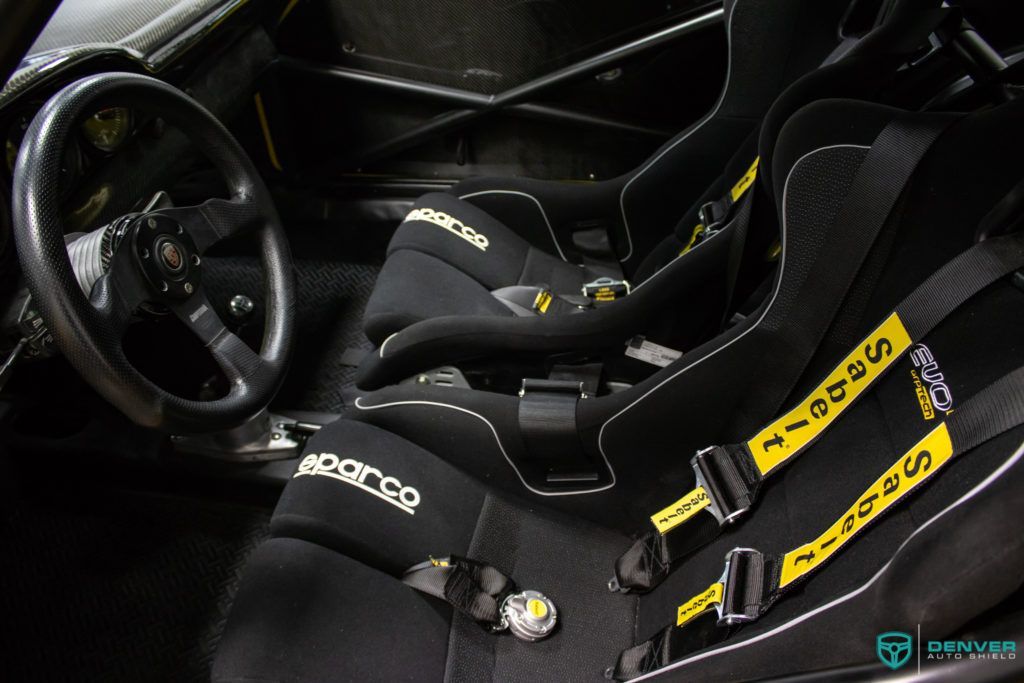 The inside of a race car with a steering wheel and seat belts