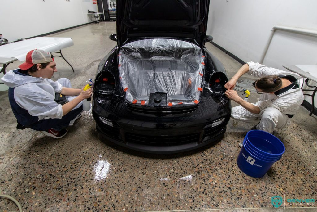 Two people are working on a car in a garage.