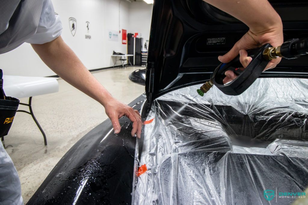 A person is wrapping a car with plastic wrap.