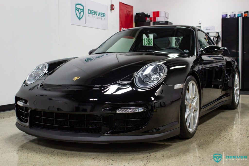 A black porsche 911 turbo is parked in a garage.