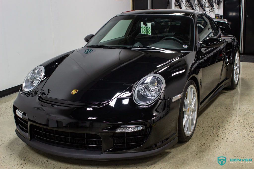 A black porsche 911 is parked in a garage.