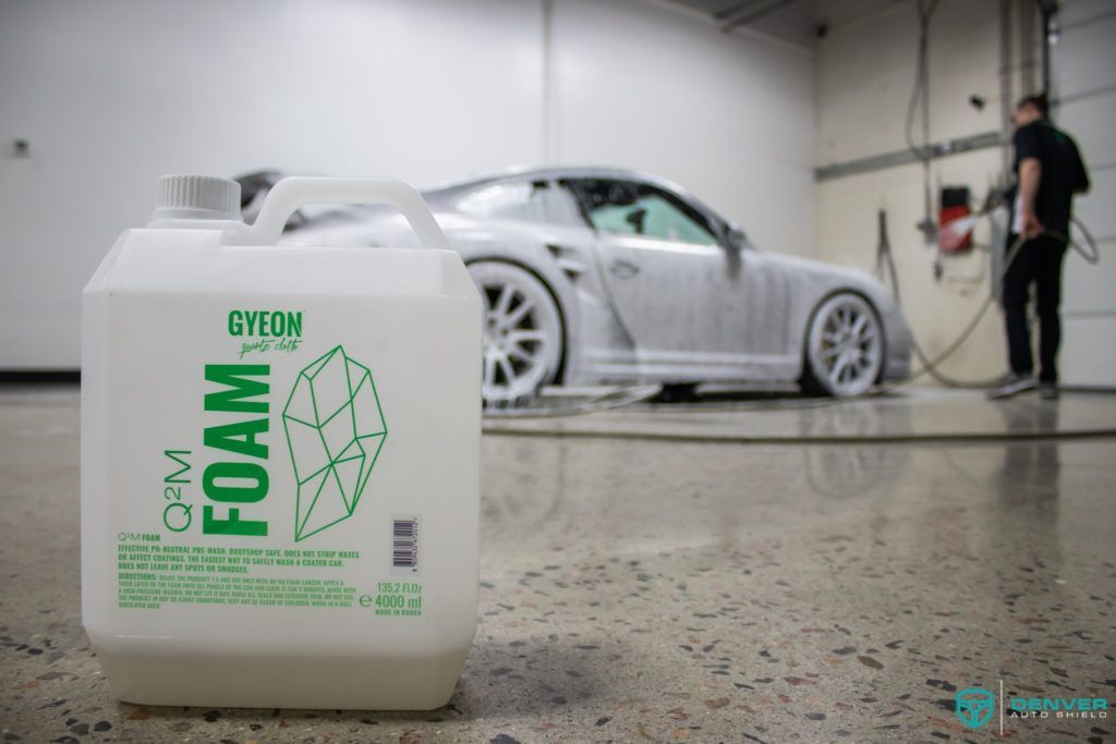 A bottle of foam is sitting next to a car in a garage.