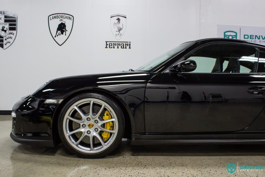 A black porsche 911 gt3 is parked in a garage.