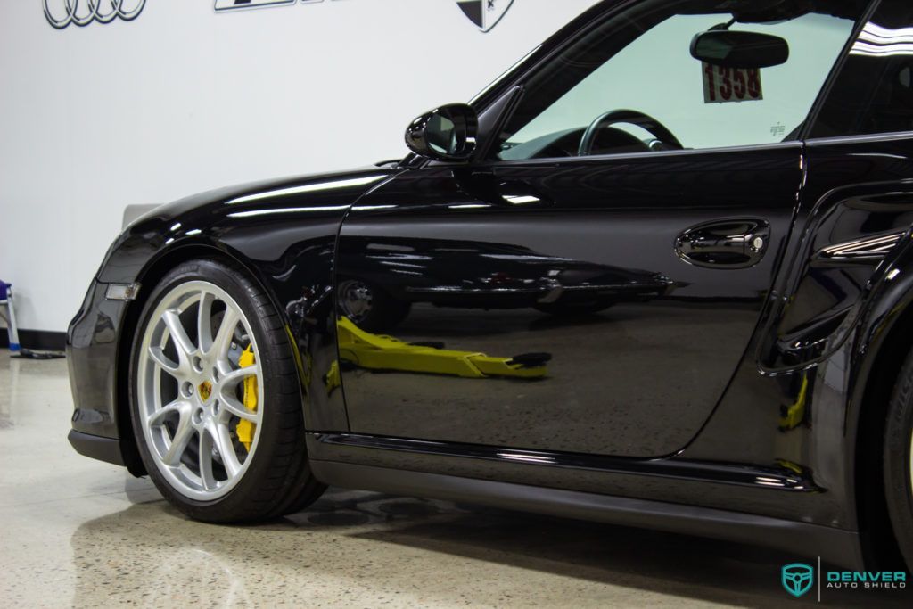 A black porsche 911 turbo is parked in a garage.