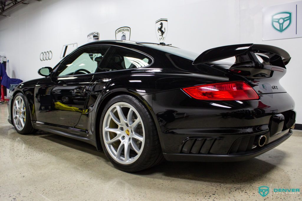 A black porsche 911 turbo is parked in a garage.