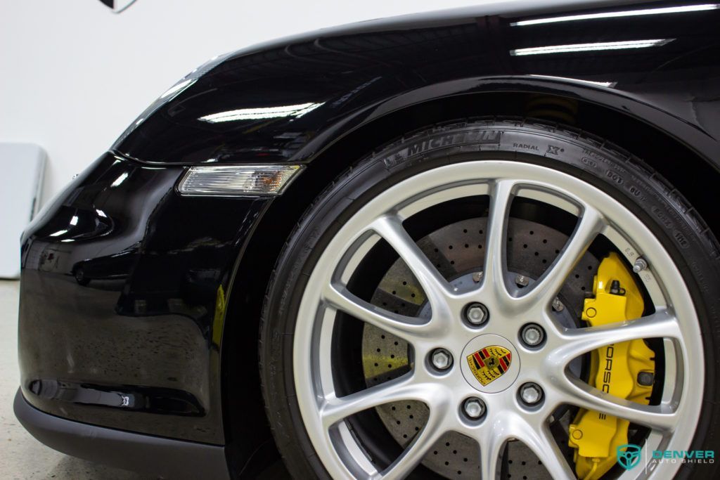 A close up of a black porsche 911 with yellow brake calipers.