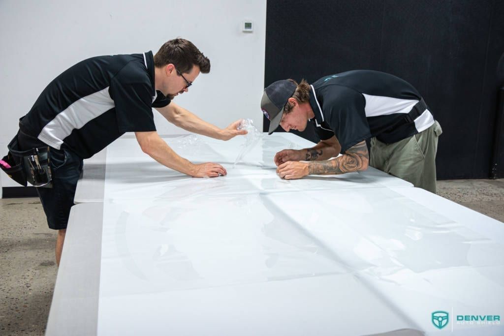 Two men are working on a large piece of white paper.