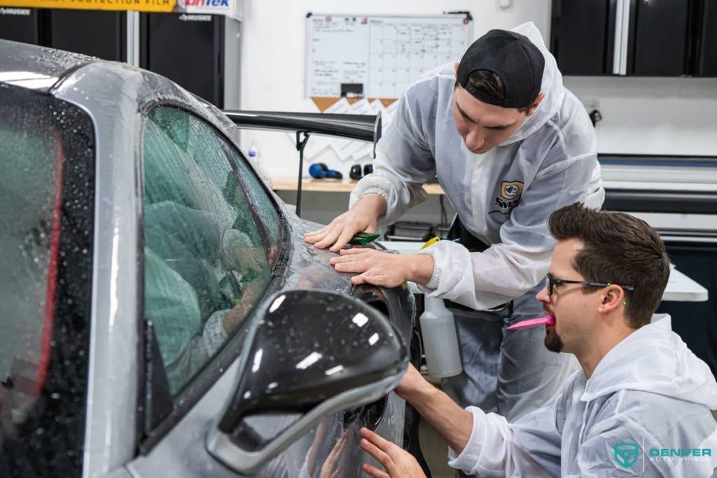 Two men are working on a car in a garage.