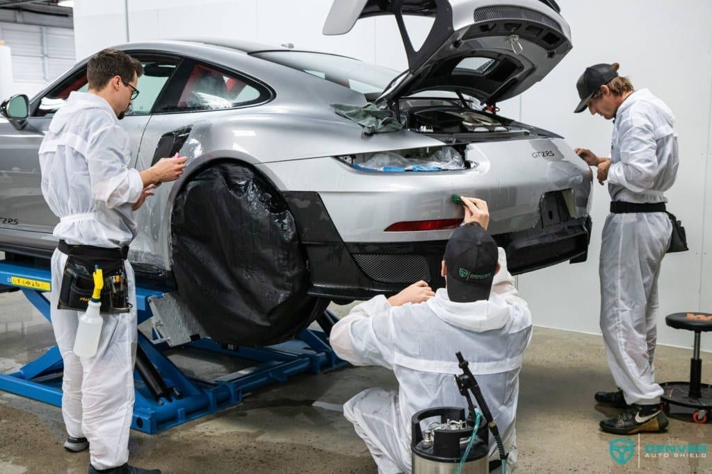 A group of men are working on a car in a garage.