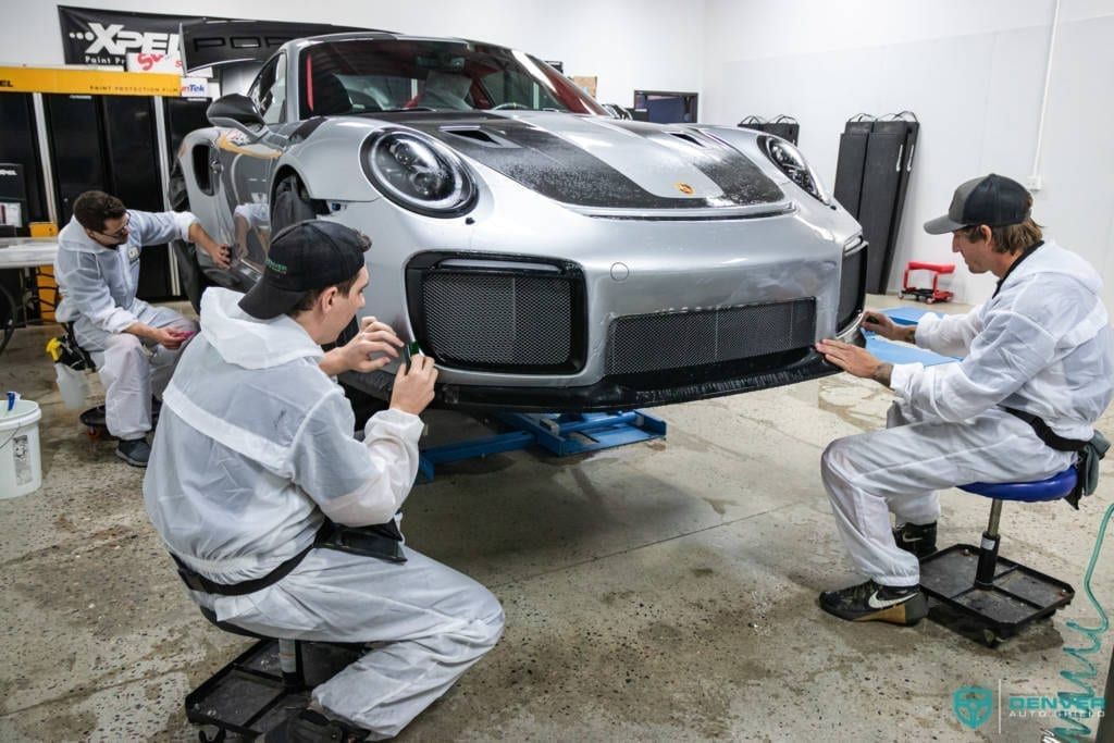 A group of men are working on a car in a garage.