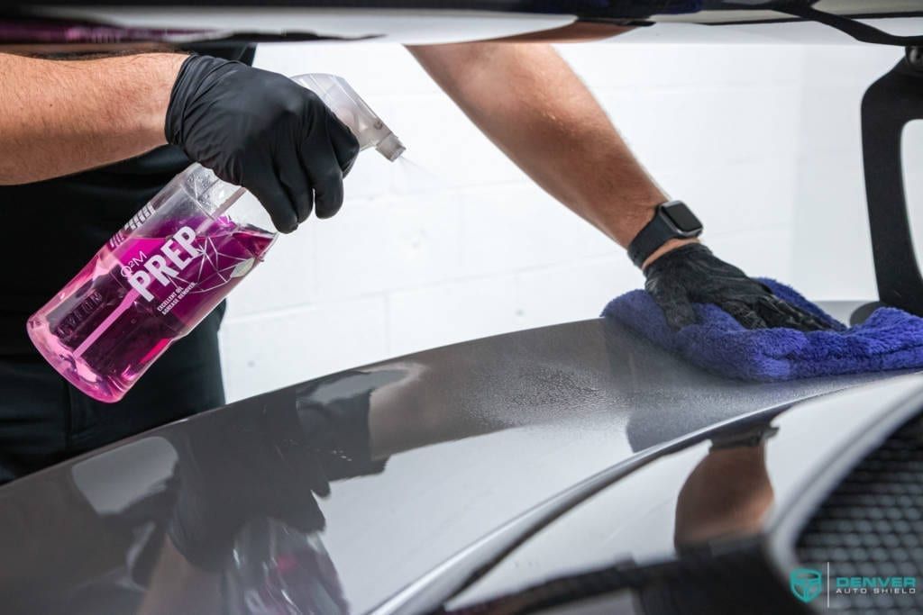 A man is cleaning a car with a cloth and a spray bottle.