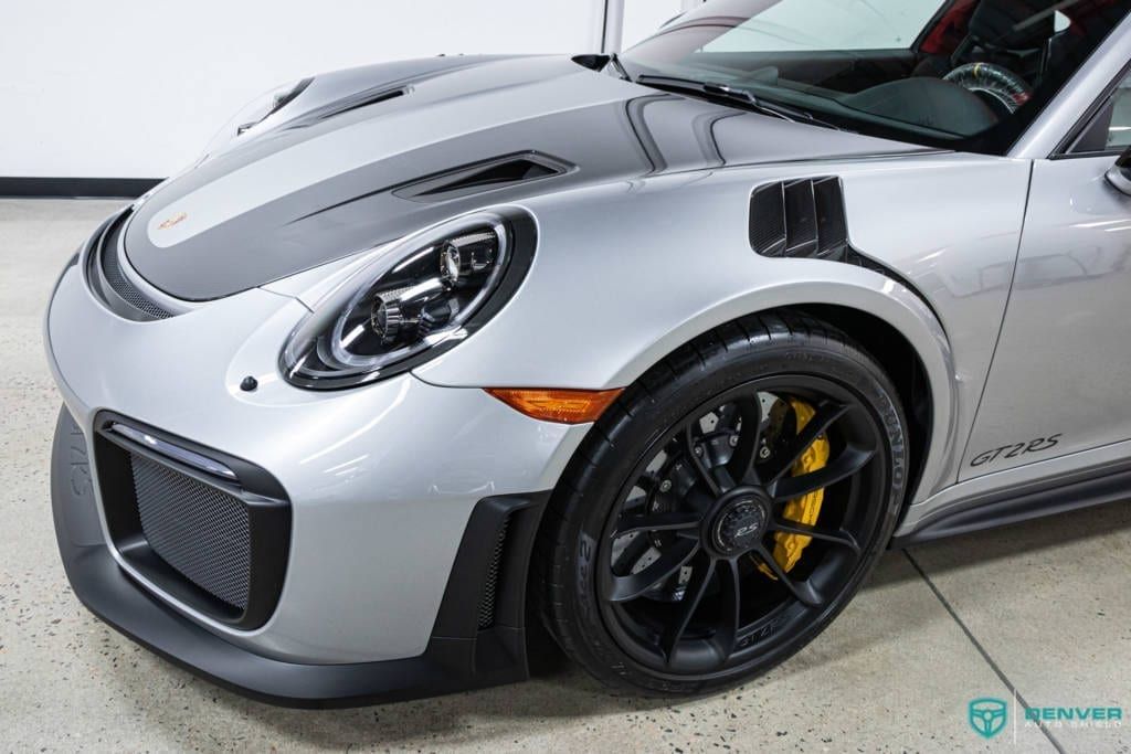 A silver porsche 911 gt2 rs is parked in a garage.