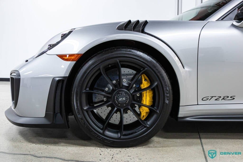 A silver porsche 911 gt2 rs is parked in a garage.