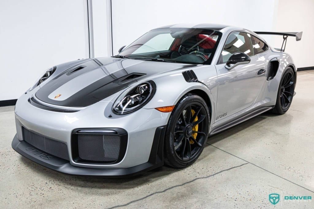 A silver porsche 911 gt2 rs is parked in a garage.