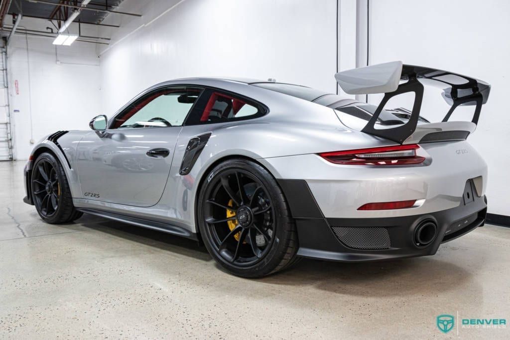 A silver porsche 911 gt2 rs is parked in a garage.