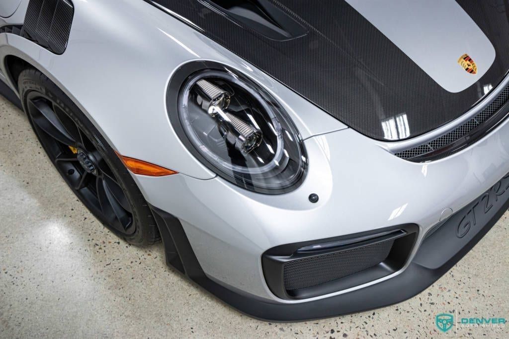 A silver porsche 911 gt2 rs is parked in a garage.