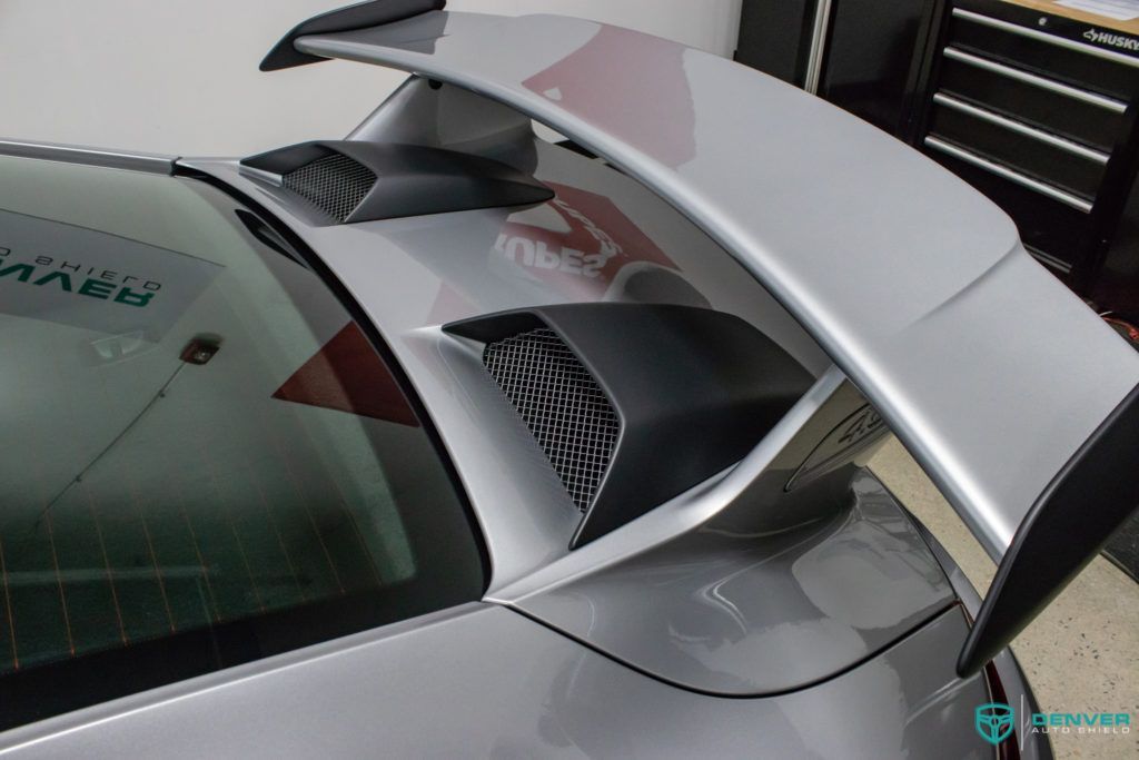 A silver car with a black spoiler on the back