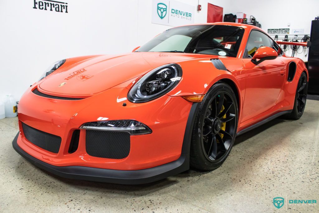 An orange porsche 911 gt3 rs is parked in a garage.