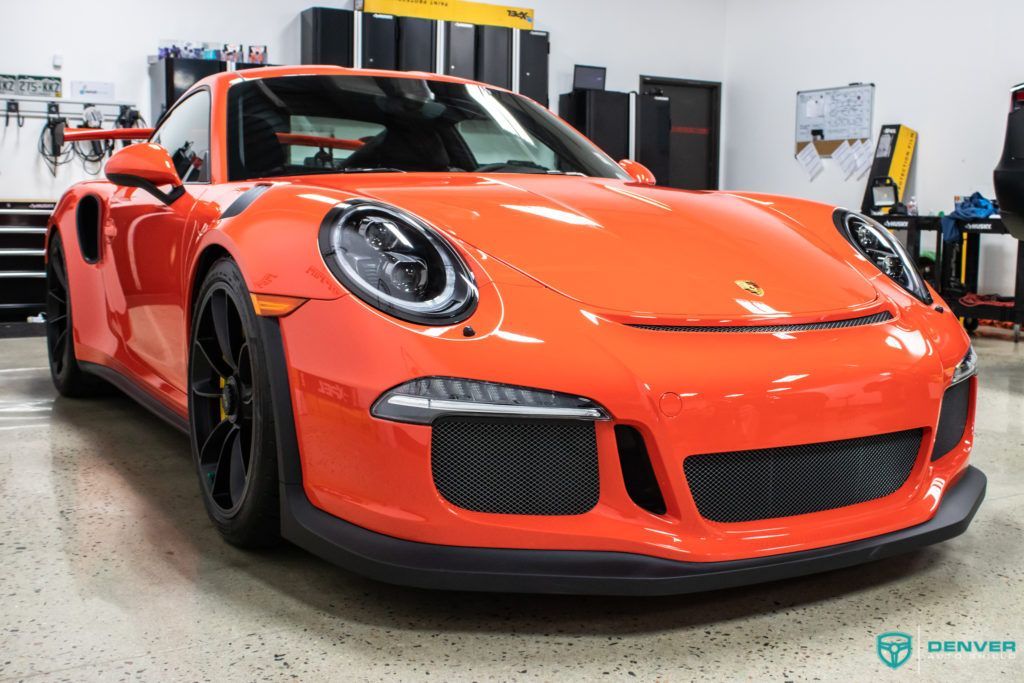 An orange porsche 911 gt3 rs is parked in a garage.