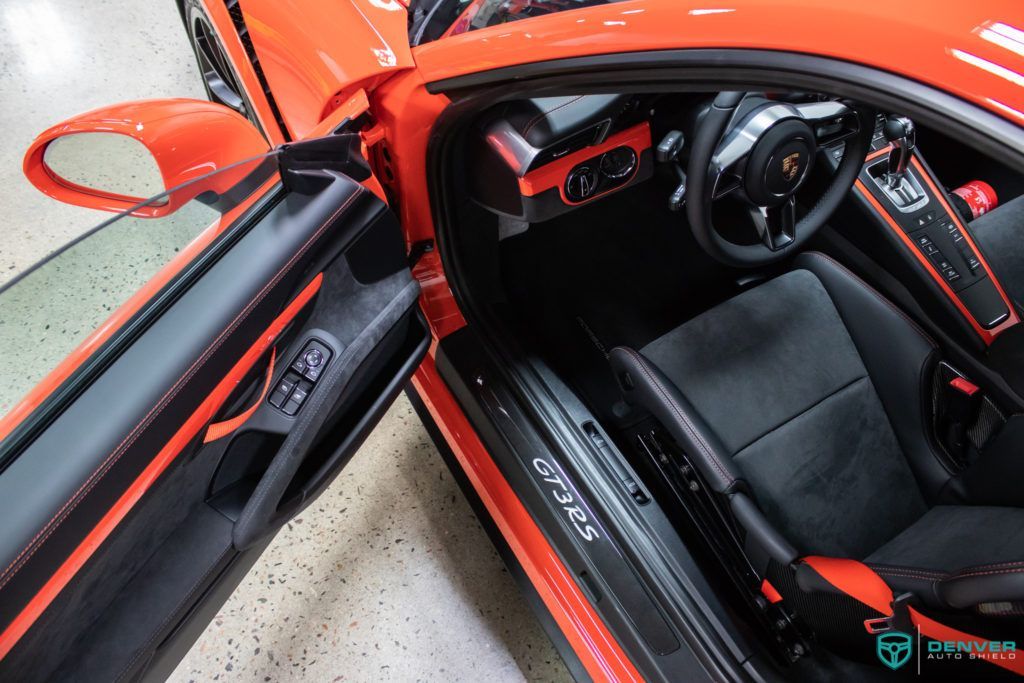 The interior of an orange porsche 911 gt3 rs with the door open.