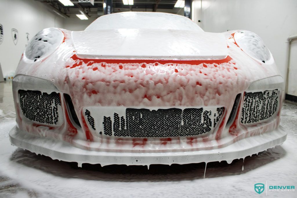 A car is covered in foam in a garage.