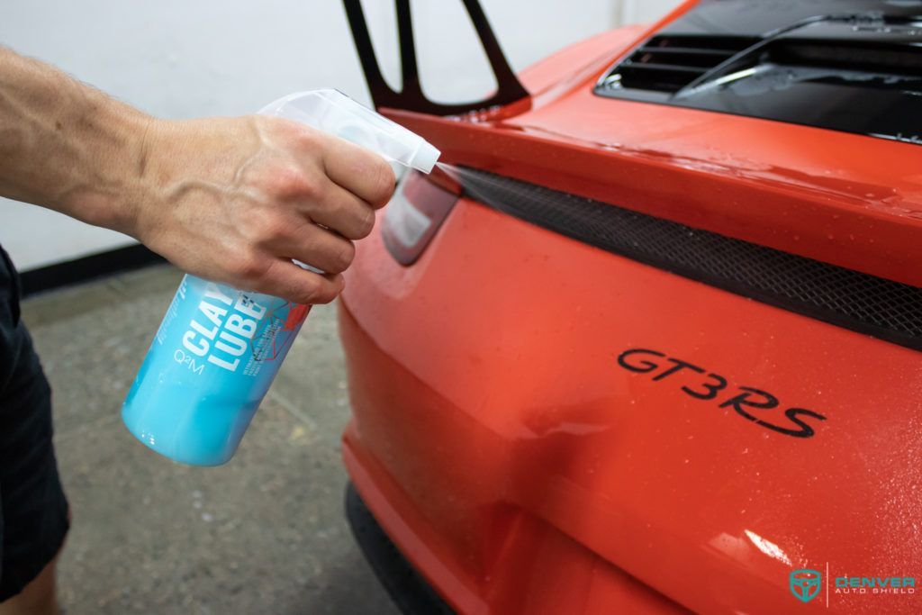 A person is spraying a car with a spray bottle.