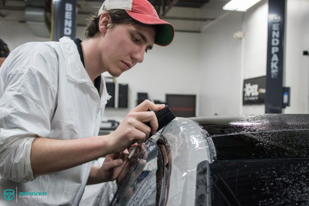 A young man is working on a car in a garage.