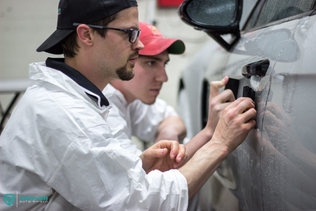 Two men are working on a car in a garage.