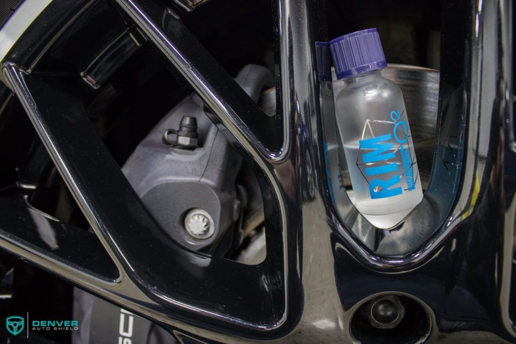 A bottle of liquid is sitting on top of a car wheel.