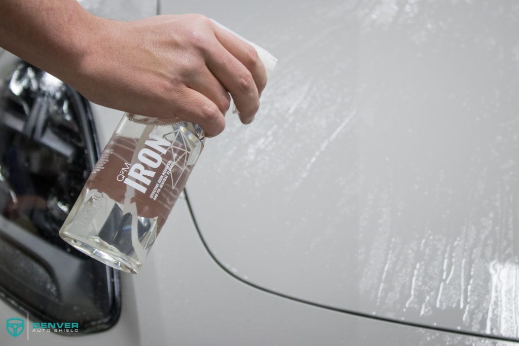 A person is cleaning a car with a bottle of cleaner.