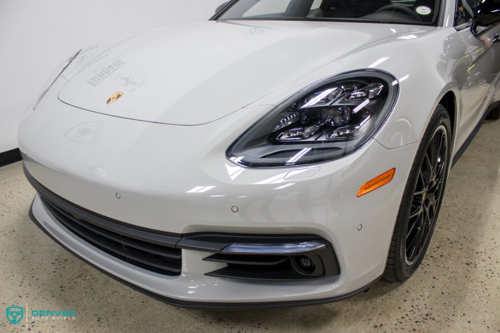 A white porsche panamera is parked in a garage.